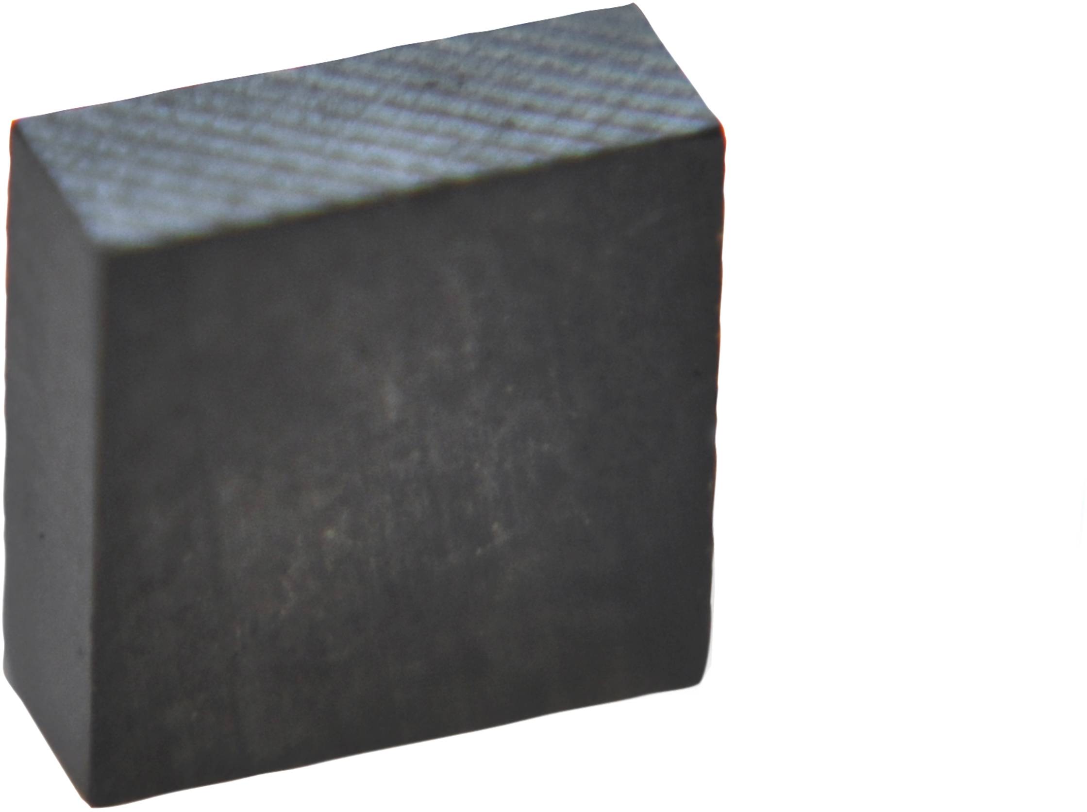 Malý, obdélníkový magnetický blok z feritového materiálu, tmavě šedý a lehce strukturovaný.
