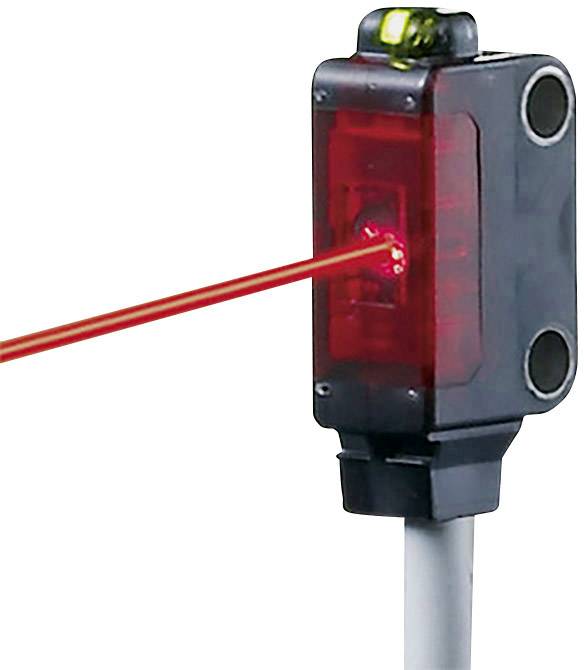 Červený laserový paprsek vyzařuje z obdélníkového senzorového zařízení připevněného k bílému kabelu.