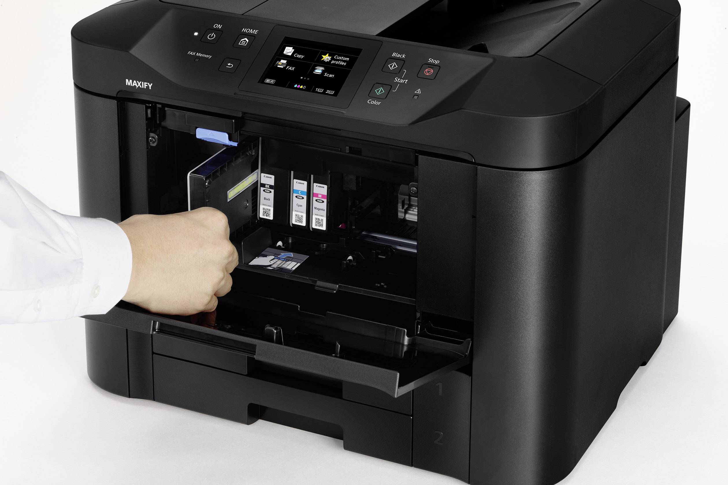 Osoba vyměňuje sadu inkoustových kazet černé multifunkční tiskárny. Tiskárna má digitální ovládací panel nahoře.