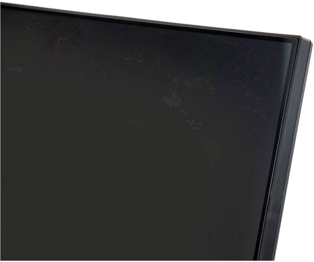 Detailní záběr černého monitoru s úzkou lištou, tmavé pozadí v pozadí.