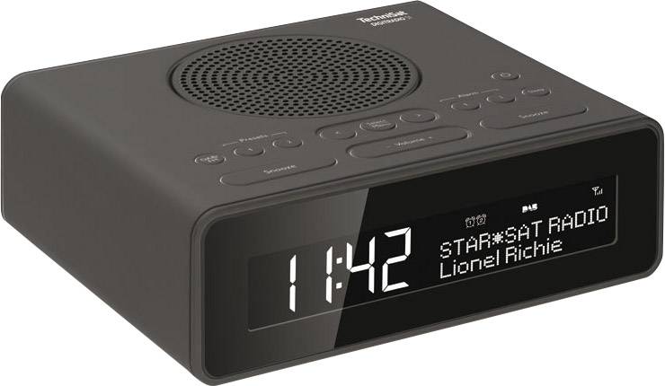 Černý digitální budík ukazuje 11:42. Na displeji je nápis 'STAR*SAT RADIO' a 'Lionel Richie'. Nahoře jsou tlačítka pro nastavení.