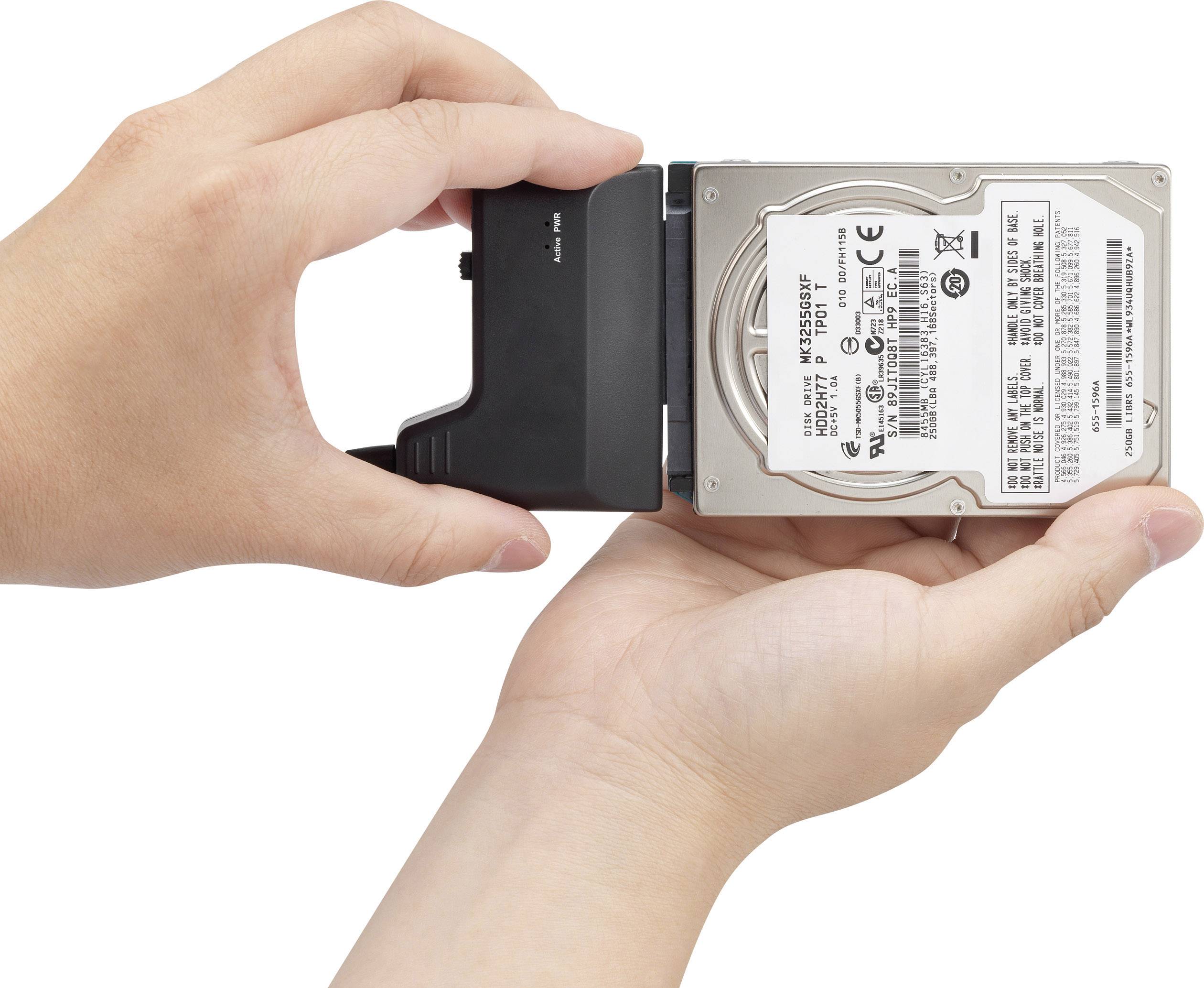 Dvě ruce drží pevný disk, který je připojen externím adaptérem. Adaptér umožňuje připojení přes USB.