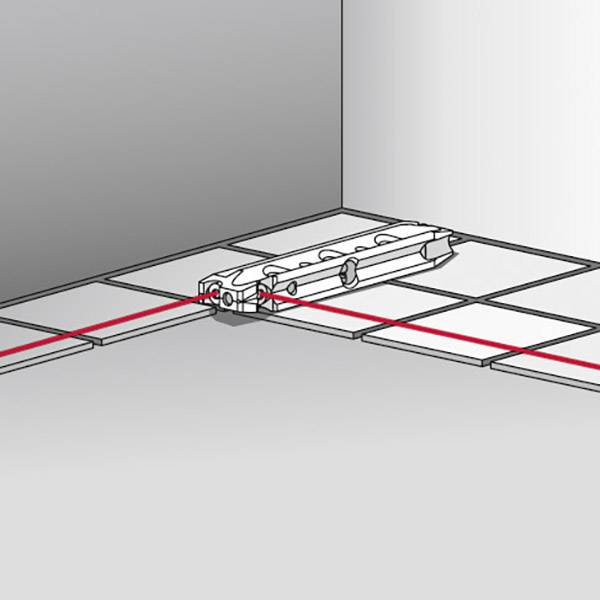 Laserová vodováha promítá červenou čáru na dlažbu a ukazuje přesné vodorovné vyrovnání. Ideální pro pokládku obkladů.