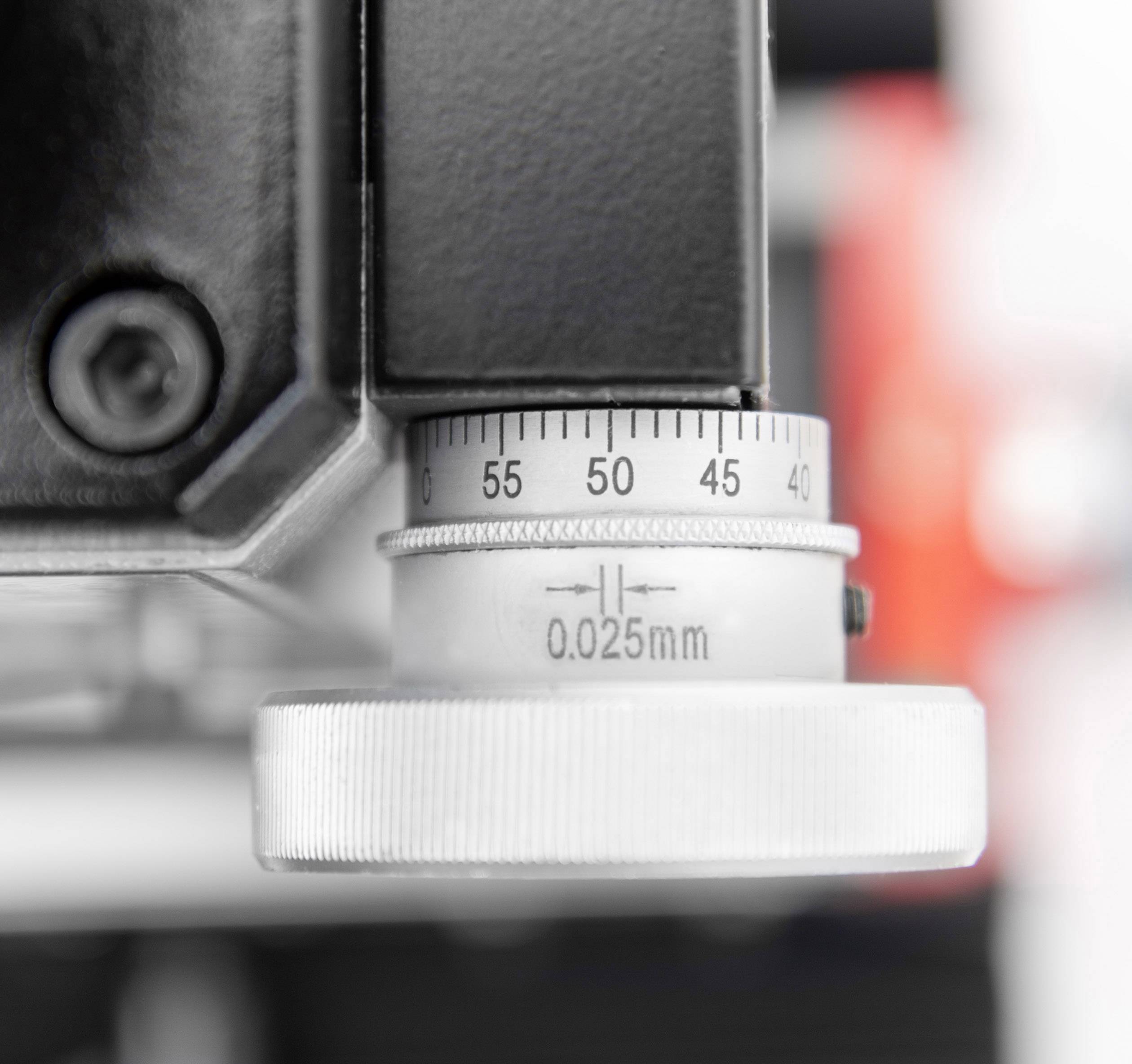 Detailní záběr mechanismu se stupnicí od 40 do 55 a označením '0,025 mm'. Nastavovací kolečko a upevňovací šroub jsou viditelné.