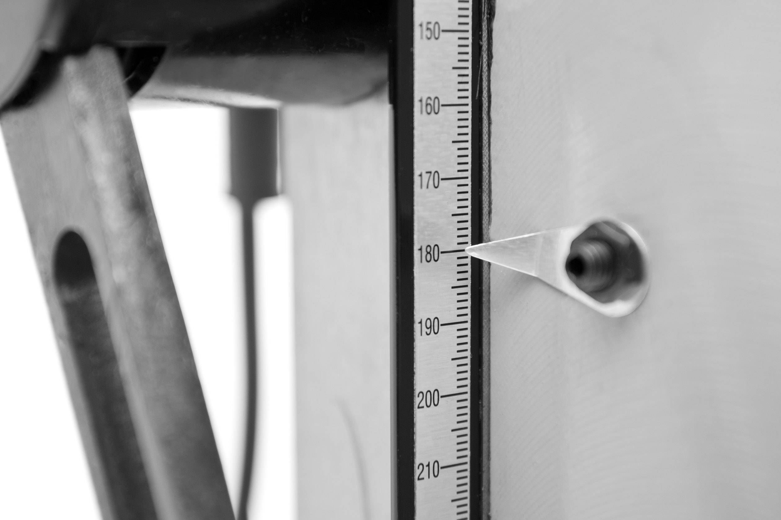 Detailní záběr výškoměru se stupnicí v milimetrech. Ručička ukazuje na 180 mm. Připevněno na mechanickém přístroji.