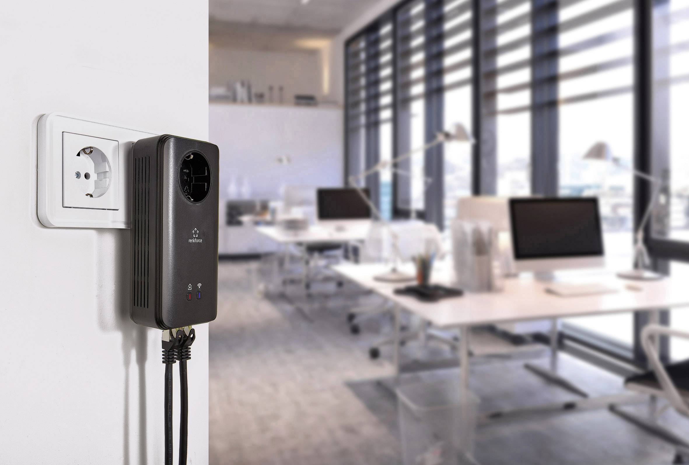 Regulátor napětí je zapojen do elektrické zásuvky v moderní kanceláři. V pozadí jsou psací stoly a počítače.