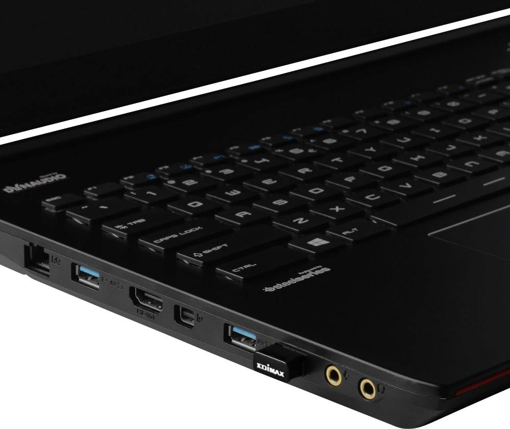 Notebook s připojenou černou USB rozšiřující kartou. Viditelná levá boční lišta s porty a částečně klávesnice.