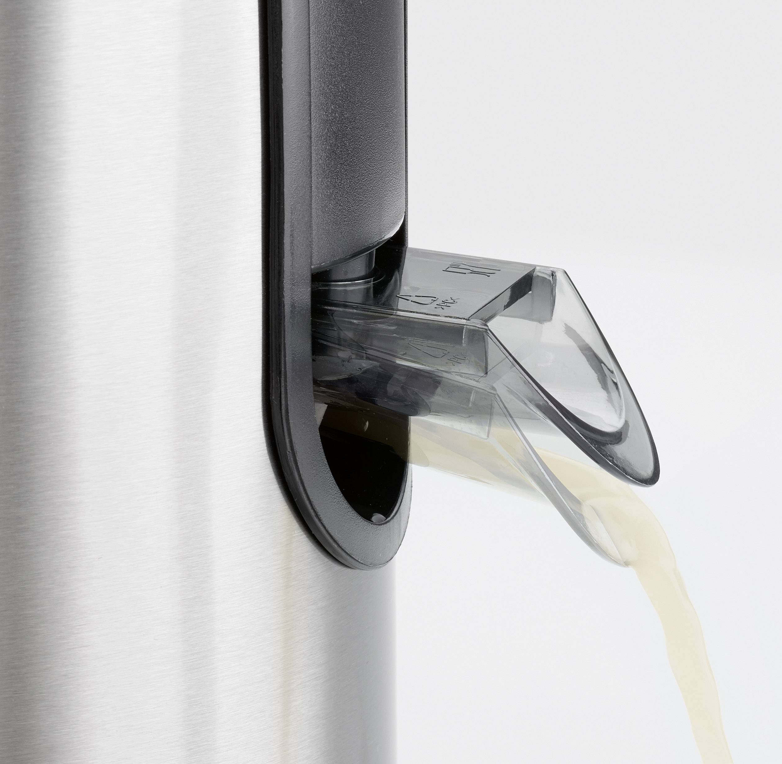 Detail nerezové elektrické odšťavňovače citrusů při práci, který vylévá šťávu skrz výpust.