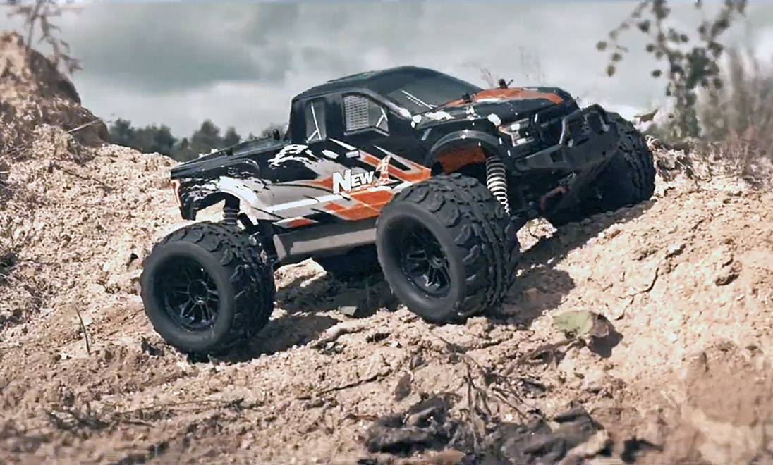 Dálkově ovládané auto jede v kopcovitém terénu, s důrazem na své velké pneumatiky a robustní karosérii.