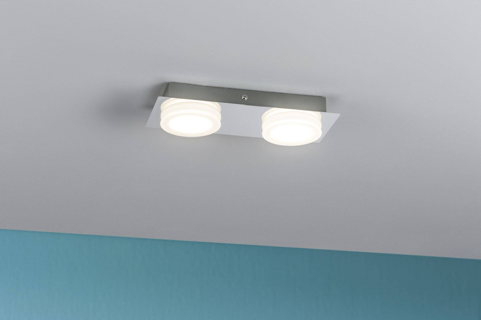 Moderní stropní lampa se dvěma kruhovými svítidly na kovovém držáku, připevněná k bílému stropu.