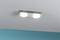 Moderní stropní lampa se dvěma kruhovými svítidly na kovovém držáku, připevněná k bílému stropu.