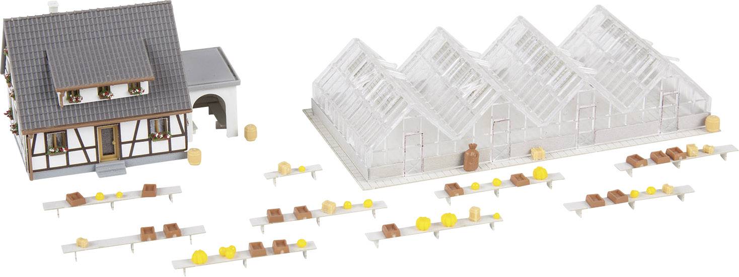 Model selského stavení s hrázděným domem, skleníky a stoly, na kterých jsou umístěny žluté a hnědé předměty.