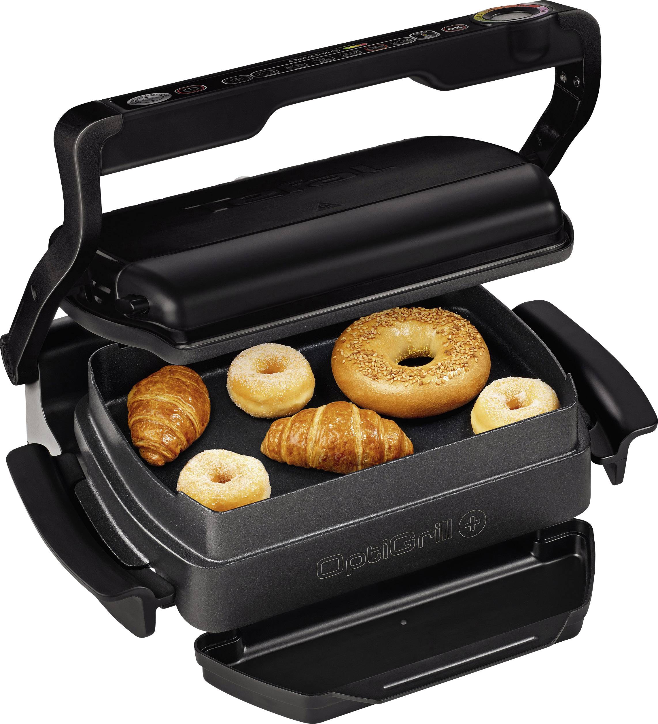 Elektrický gril s otevřeným víkem, na kterém leží bagel, dva donuty a dva croissanty.
