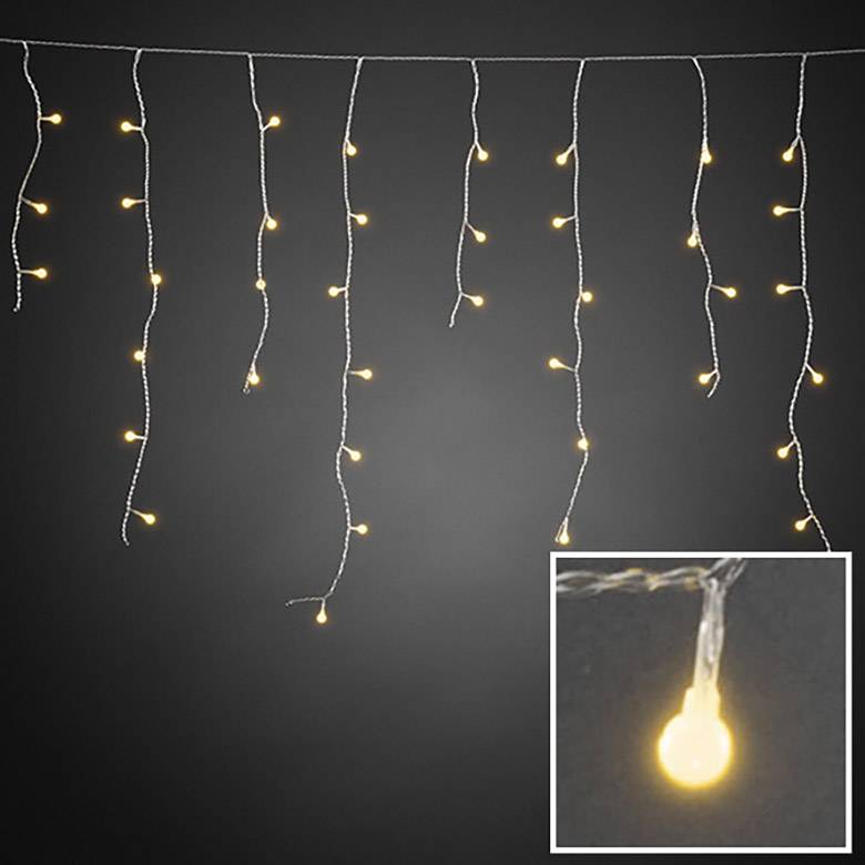 Řetěz světel s teple bílými LED žárovkami visí na šňůře. Zaměření na jedno zářící světlo v detailním záběru.