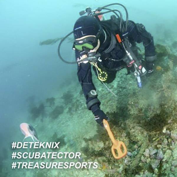 Potápěč s oranžovou lopatkou pátrá na mořském dně. Vlevo plave ryba. Text: '#DETEKNIX #SCUBATECTOR #TREASURESPORTS'.