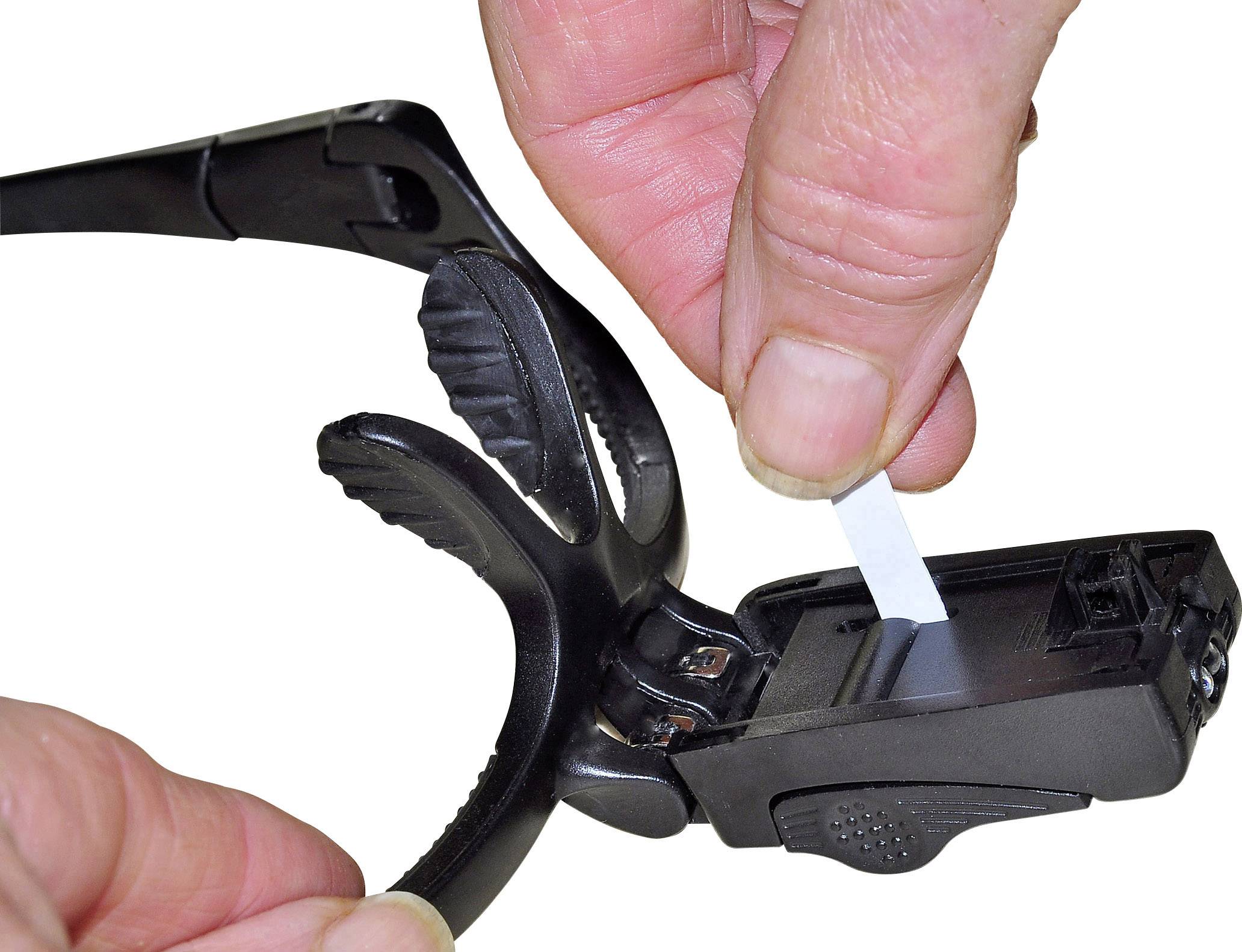 Osoba zasunuje testovací proužek do glukometru připevněného na brýlích.