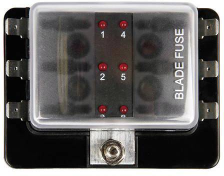 Černá pojistková skříňka s šesti červenými LED indikátory, které jsou označeny čísly 1 až 6. Vpravo je nápis 'BLADE FUSE'.