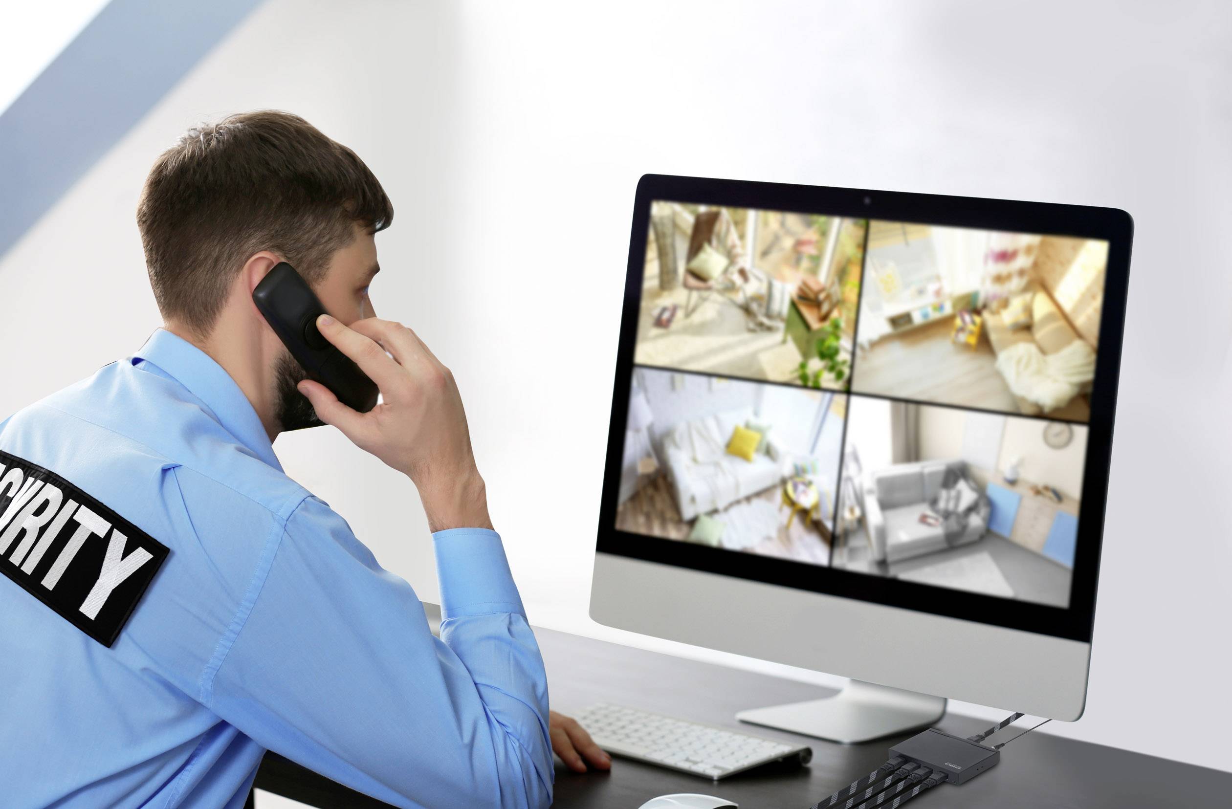 Bezpečnostní pracovník sleduje živé záběry z několika kamer na velkém počítačovém monitoru v kanceláři.