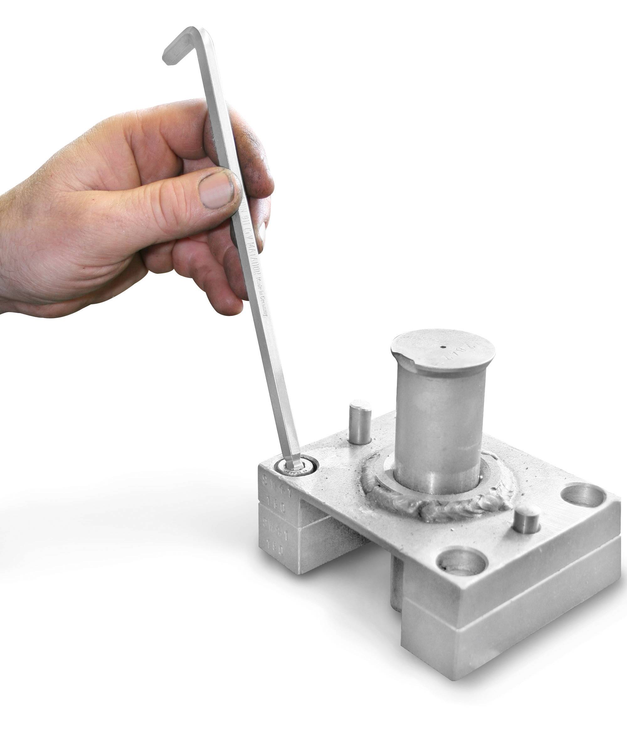 Ruka ovládá L-tvarový klíč kovový mechanismus namontovaný na stole.