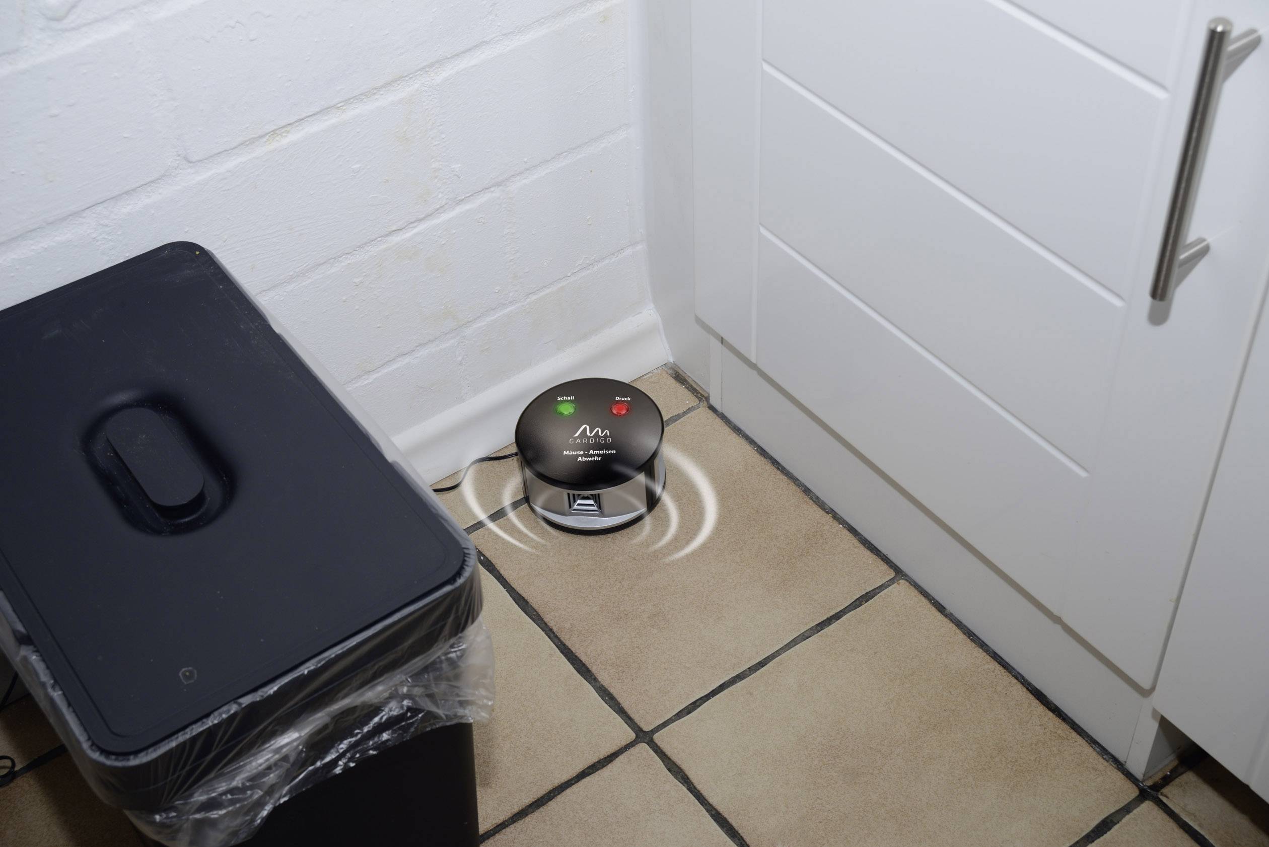 Elektronický alarm pastí na myši na podlaze kuchyně, signalizovaný svítícími indikátory.