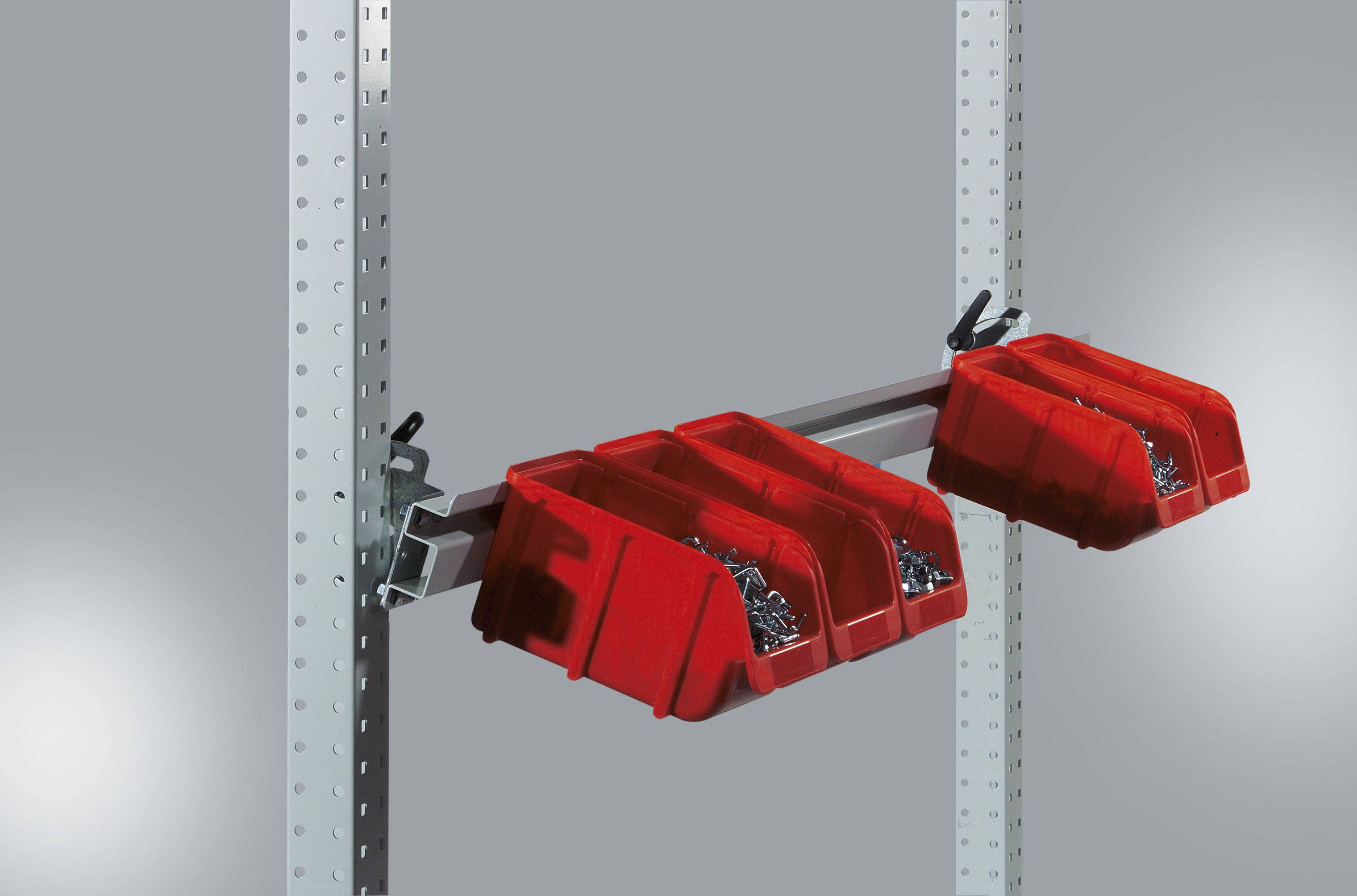 Dva červené skladovací kontejnery namontované na kovovém držáku na děrované police, naplněné malými kovovými díly, před šedým pozadím.
