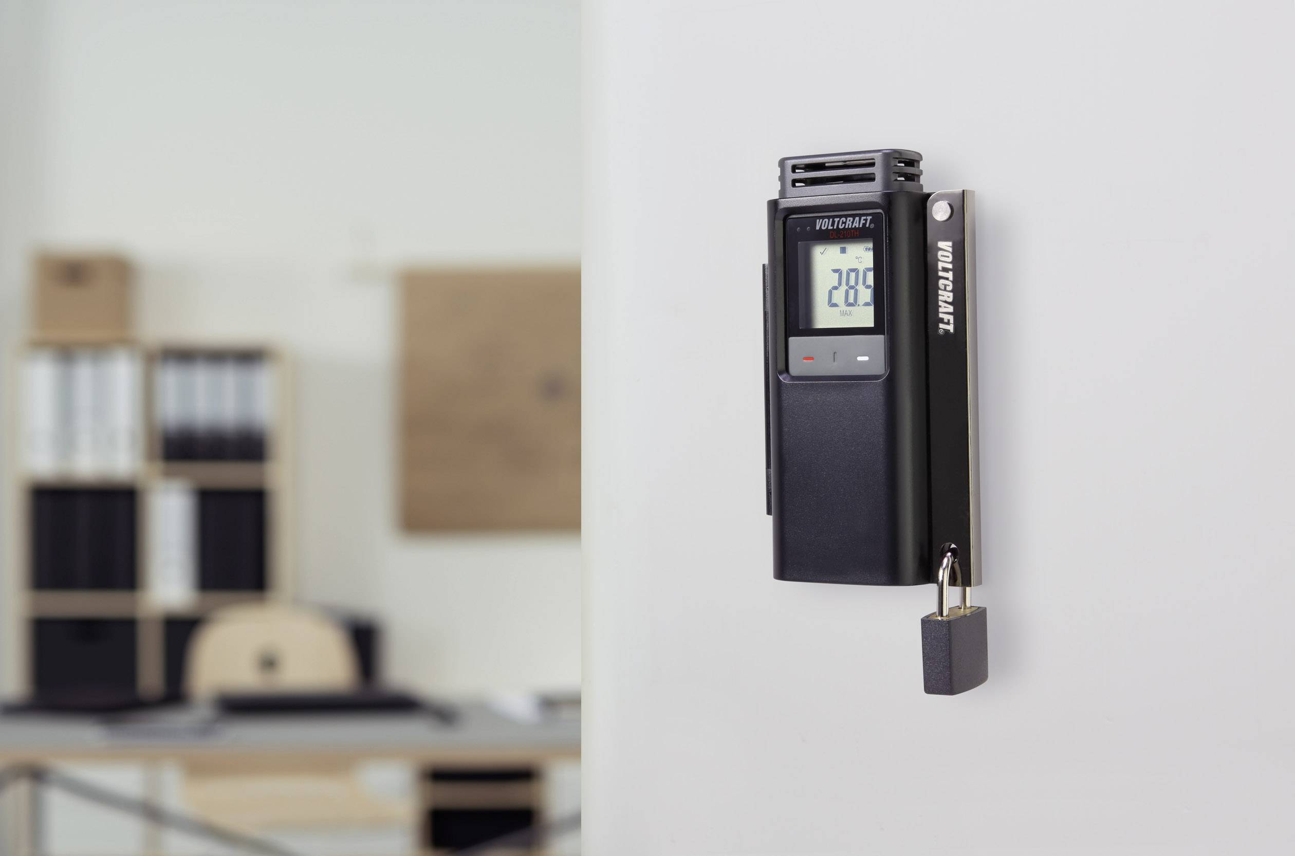 Elektronický zámek s digitálním displejem ukazuje '20.8'. V pozadí jsou vidět kancelářské vybavení.