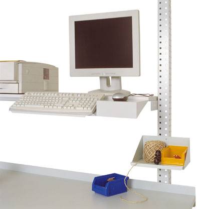 Starý stolní počítač s CRT monitorem a klávesnicí na bílém, na stěnu zavěšeném stole. Vedle žluté a modré úložné boxy.