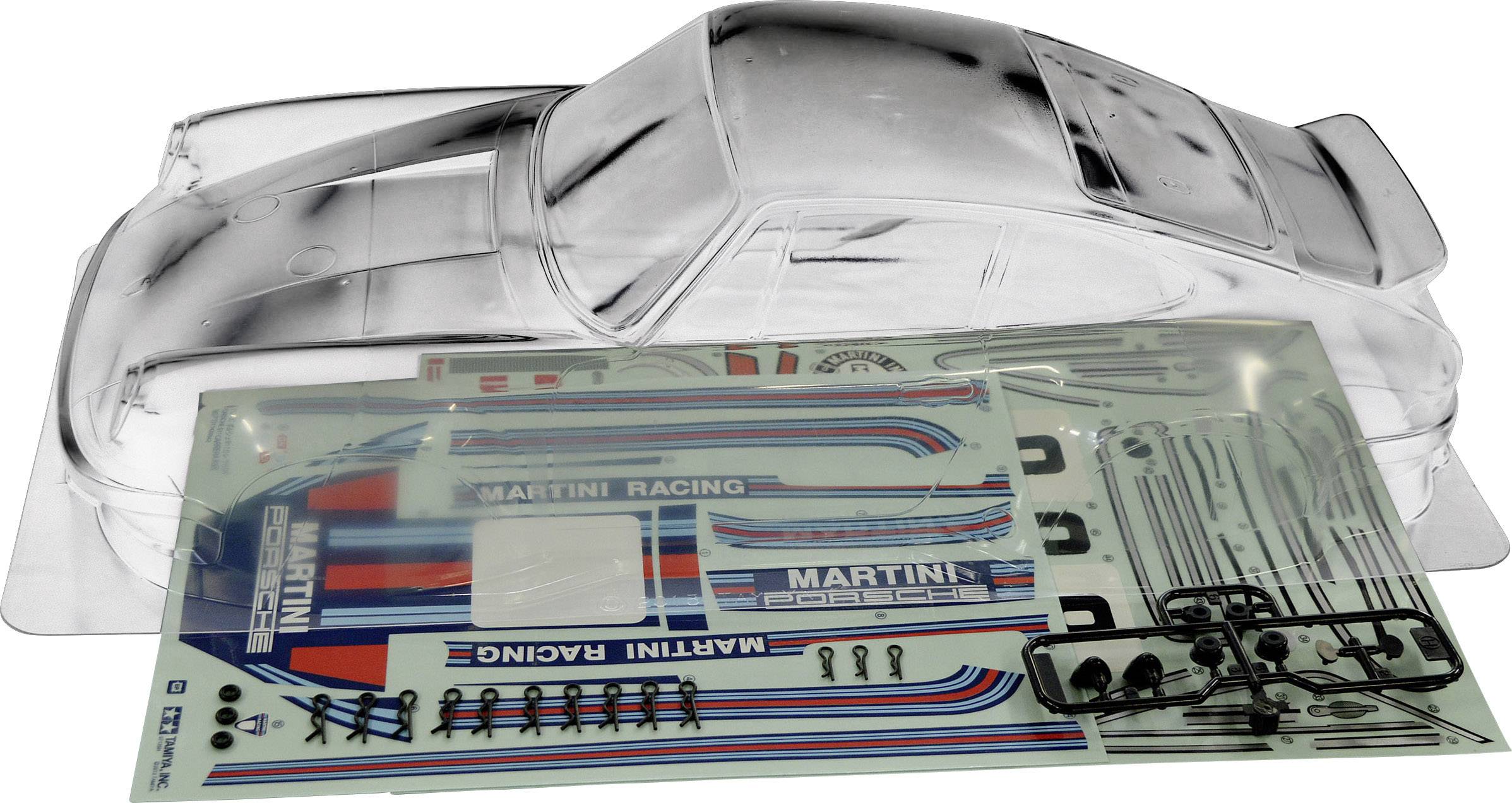 Průhledný plastový model auta vedle samolepek s nápisem 'Martini Racing' a dílů pro modelářství.