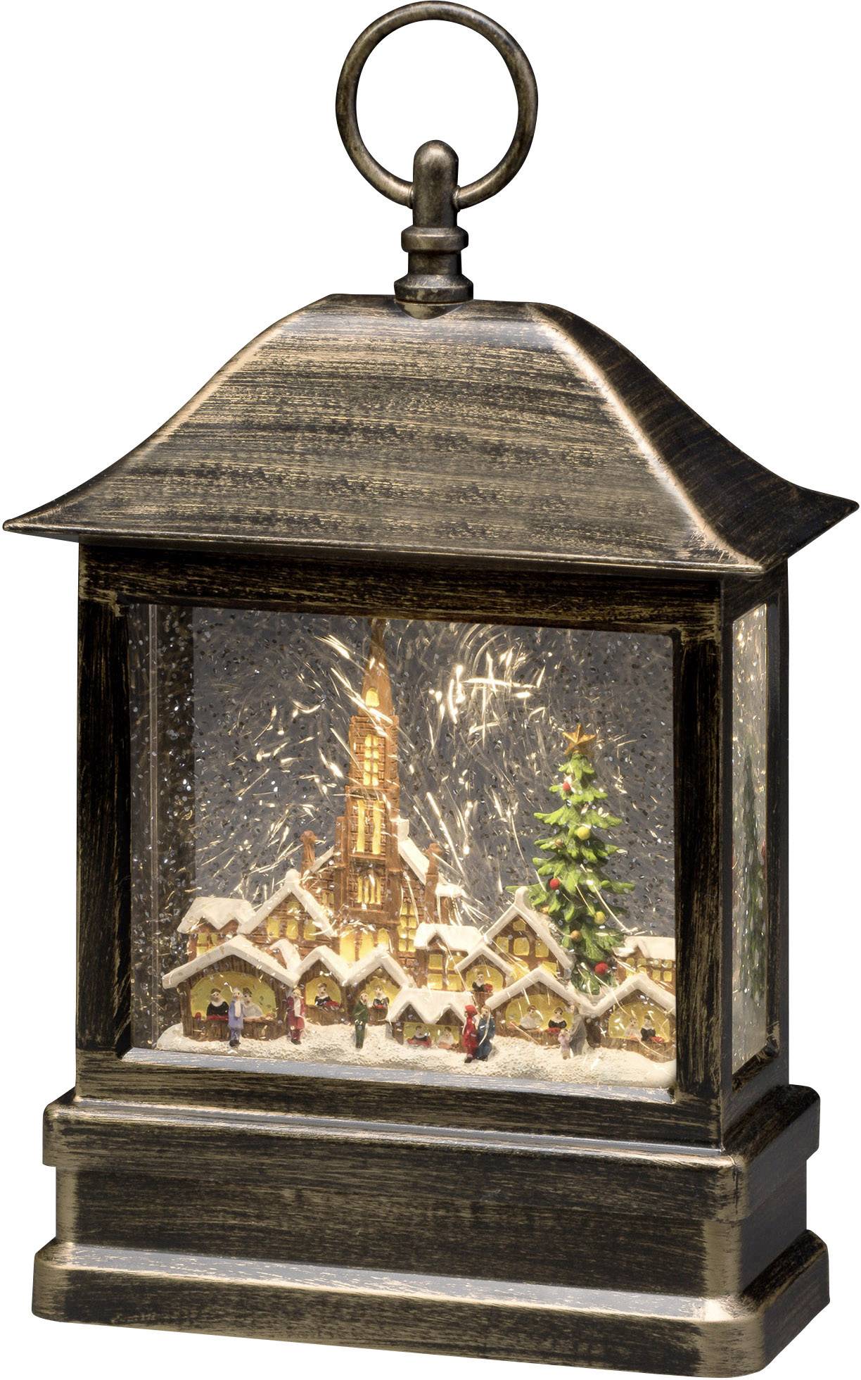 Malá lucerna s osvětlenou vánoční vesničkou, vánočním stromkem a kostelem, navozující sváteční atmosféru.