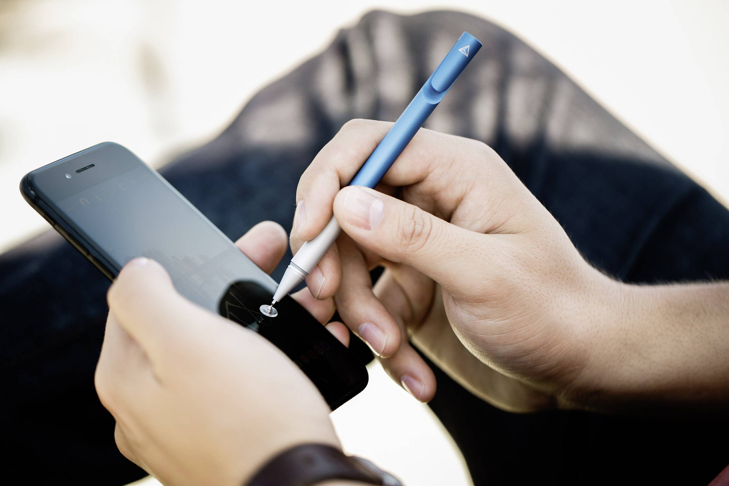 Detailní záběr rukou, které kreslí modrým perem na displeji smartphonu.