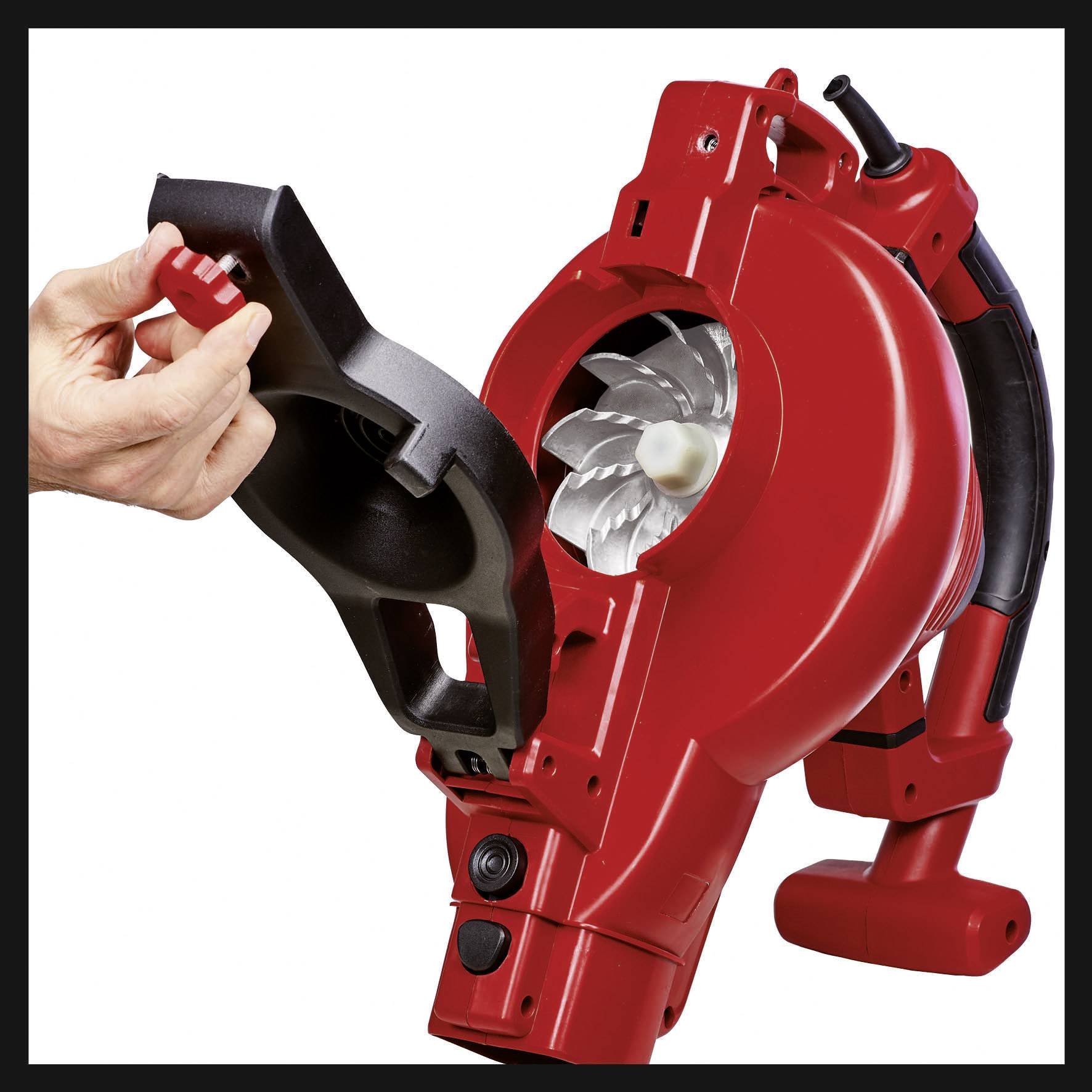 Červený foukač listí s odejmutým krytem je držen rukou. Zobrazuje pohled dovnitř turbíny.