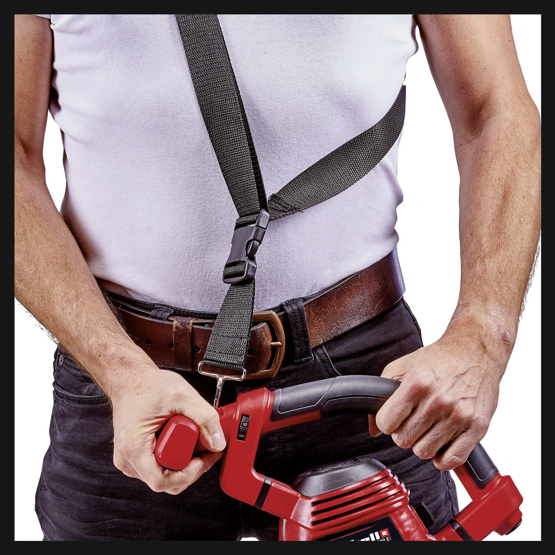 Muž v bílém tričku drží červený stroj oběma rukama, přičemž pozornost je soustředěna na způsob jeho úchopu.