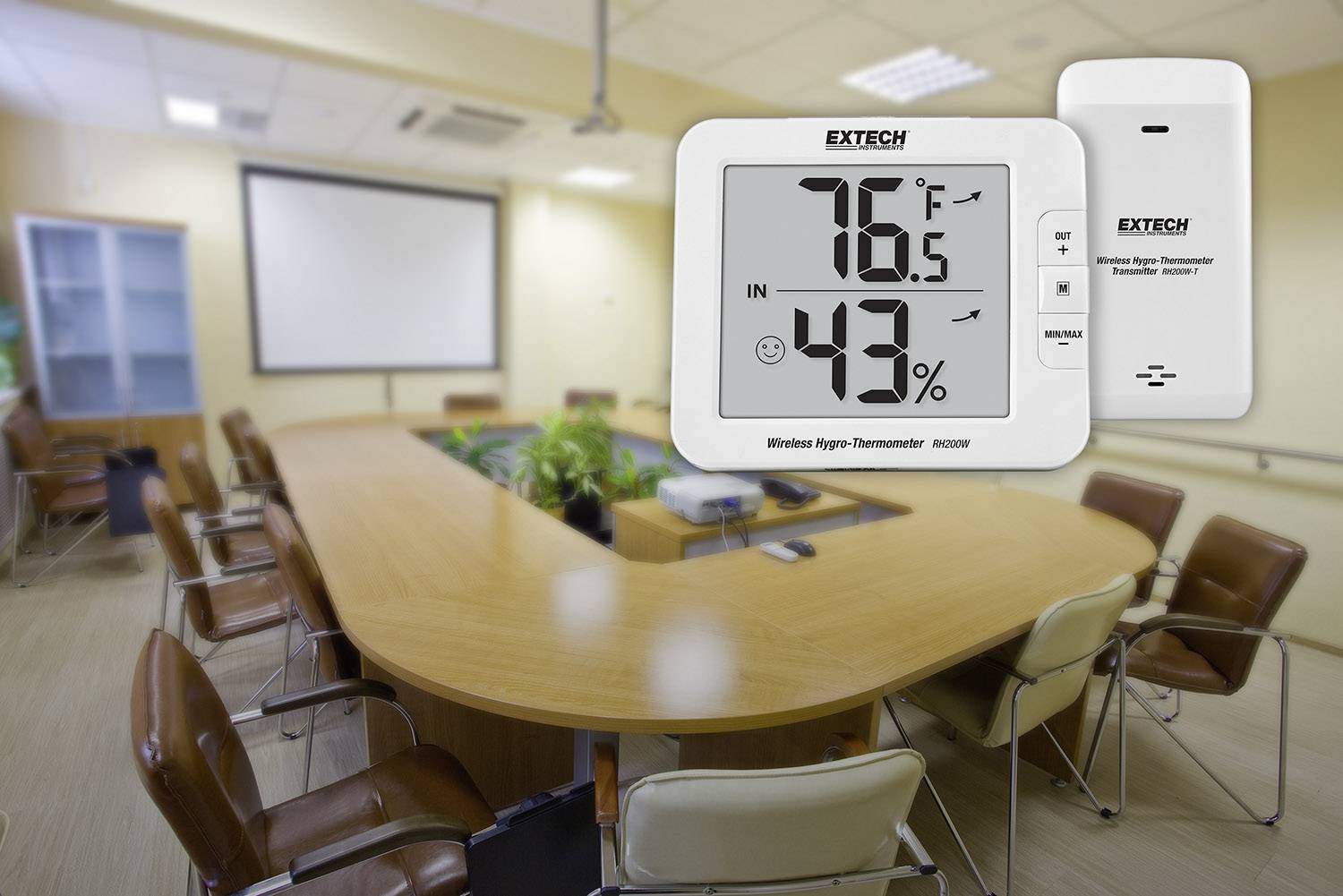 Digitální vlhkoměr ukazuje '76,5°F' a '43%'. Nachází se v prázdné konferenční místnosti s oválným stolem a několika židlemi.