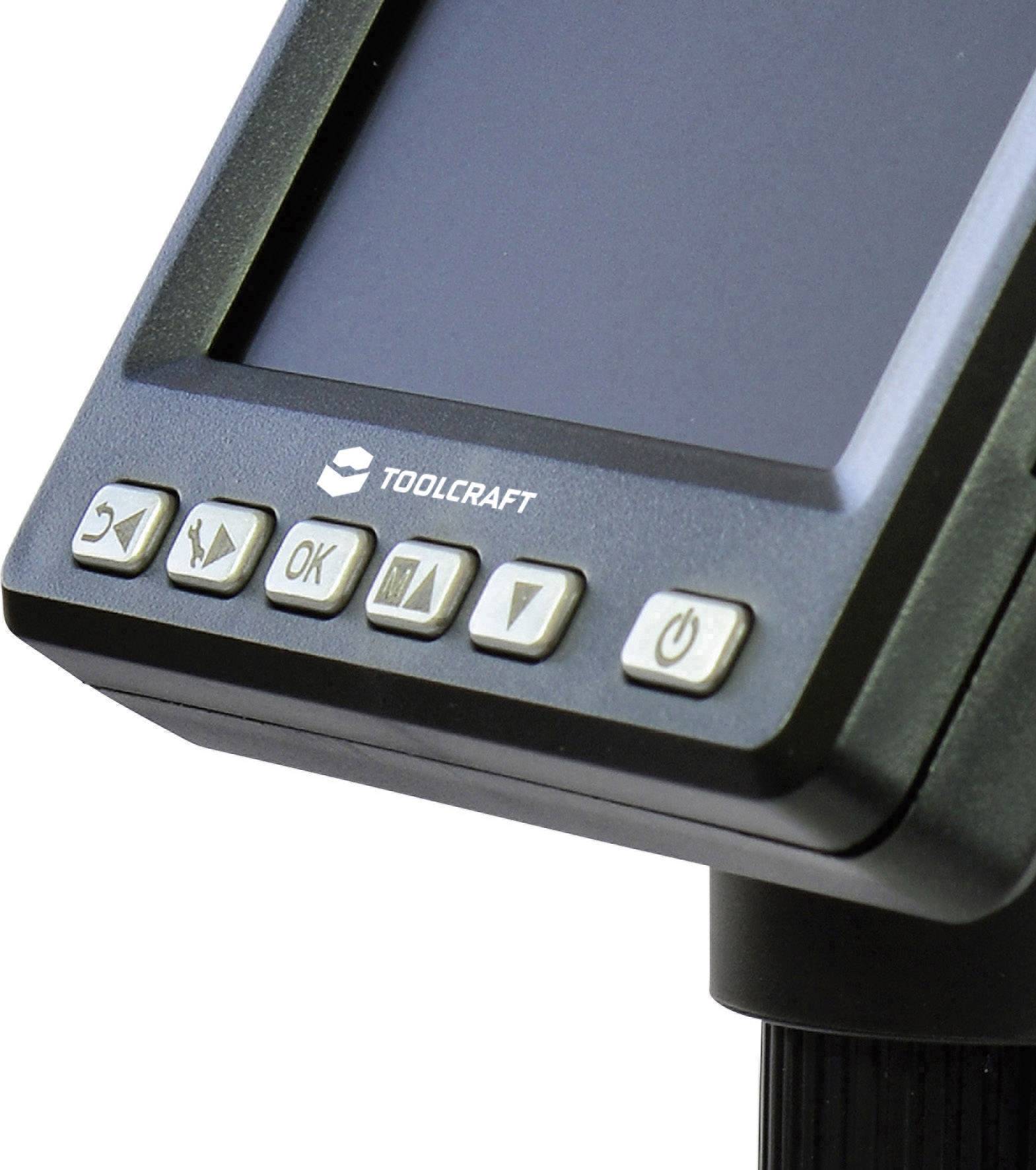 Detailní pohled na elektronické zařízení s displejem a ovládacími tlačítky, včetně tlačítka 'OK' a symbolu síťového vypínače, od značky Toolcraft.