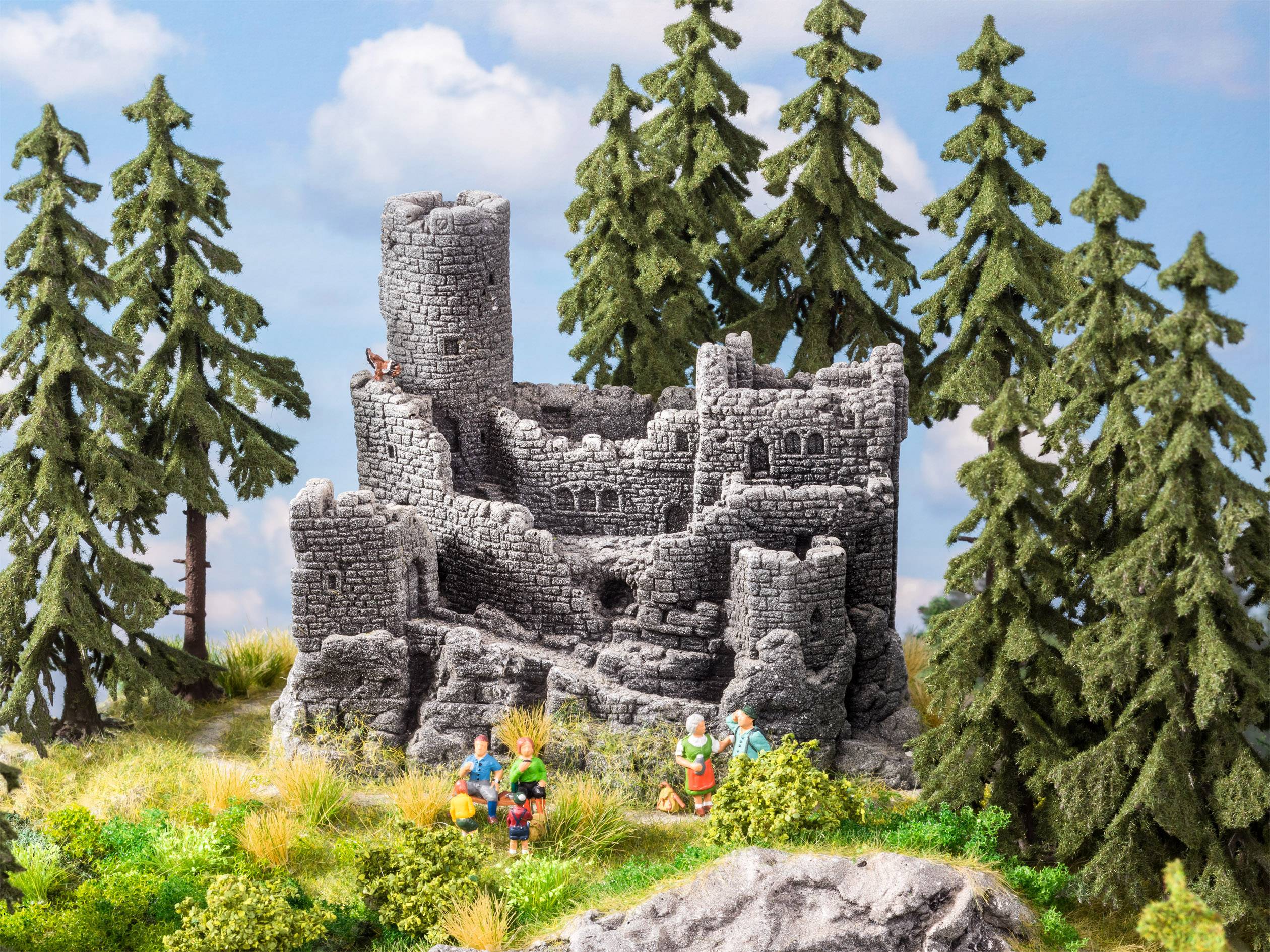 Miniaturní krajina zobrazuje zříceninu středověkého hradu obklopenou vysokými borovicemi. V popředí jsou viditelné malé figurky.