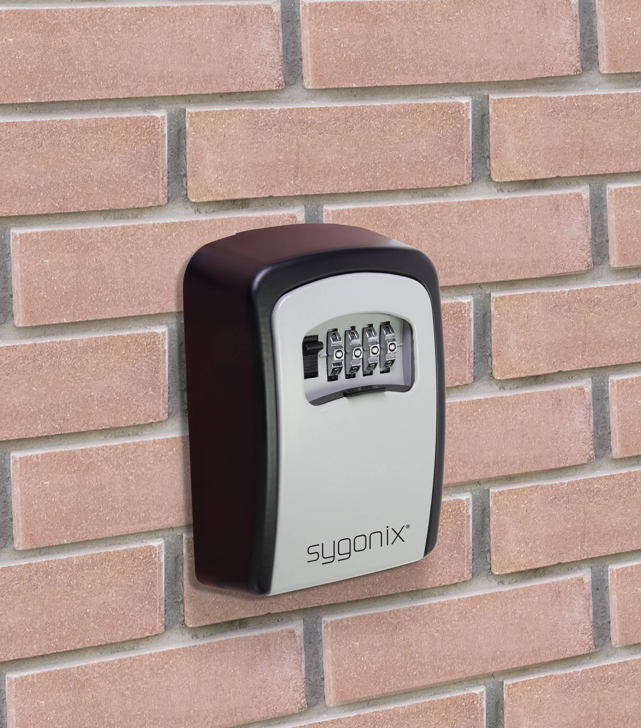 Nástěnný trezor na čísla od společnosti Sygonix je připevněn na cihlové zdi a zobrazuje mechanismus otevírání pomocí číselného kódu.