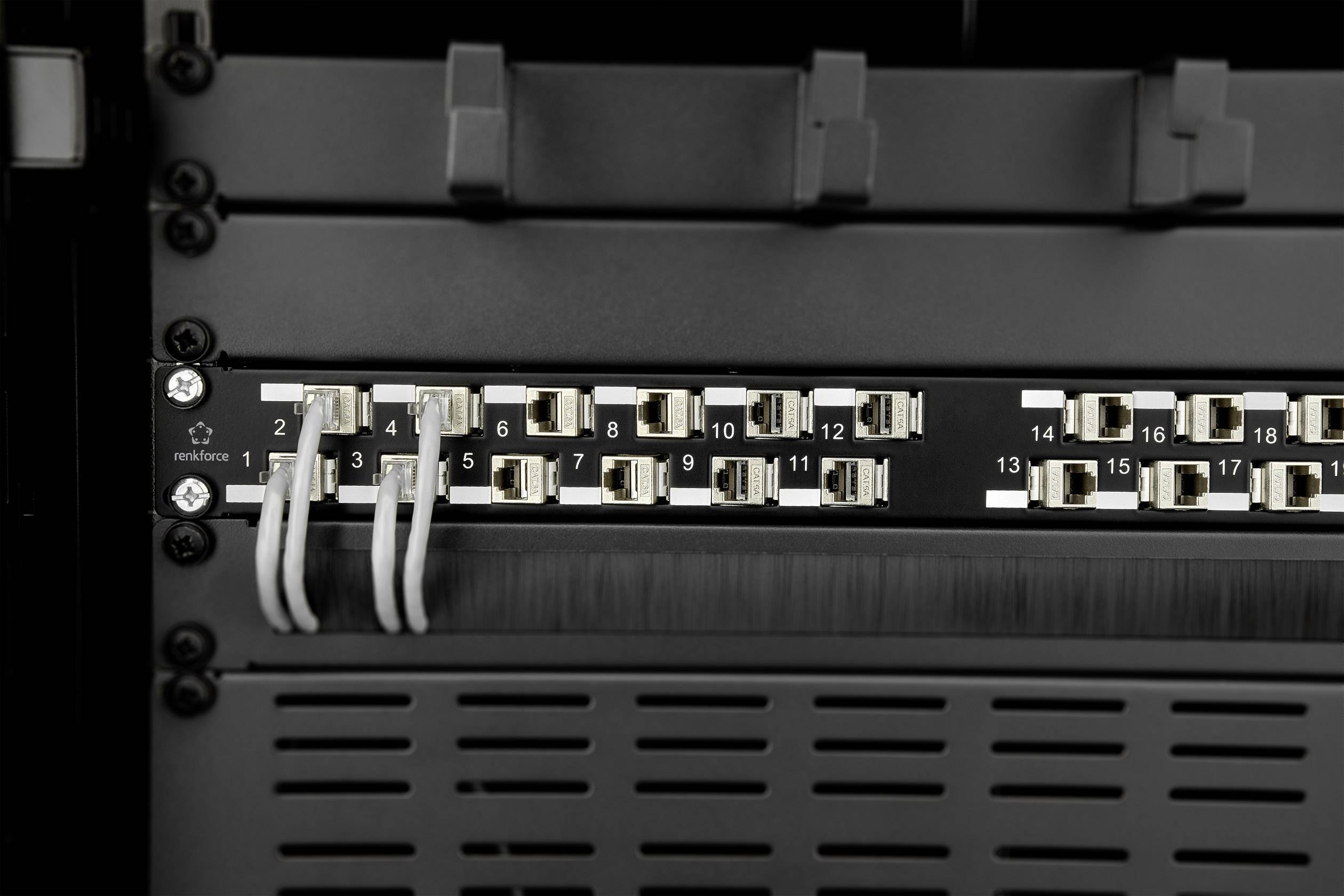Síťový rozvaděč s několika zapojenými ethernetovými kabely v různých portech, které vytvářejí propojení s různými zařízeními.
