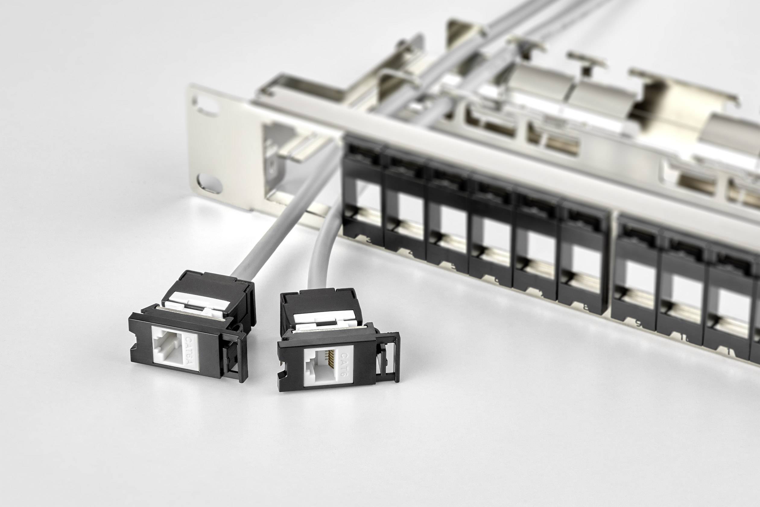 Patch panel se dvěma vytaženými síťovými konektory, obklopený dalšími přípojkami v prostředí serveru.