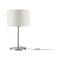 Bílá stolní lampa s válcovým stínidlem, moderní kovovou základnou a viditelným kabelem se spínačem. Moderní design vhodný pro obytné prostory.