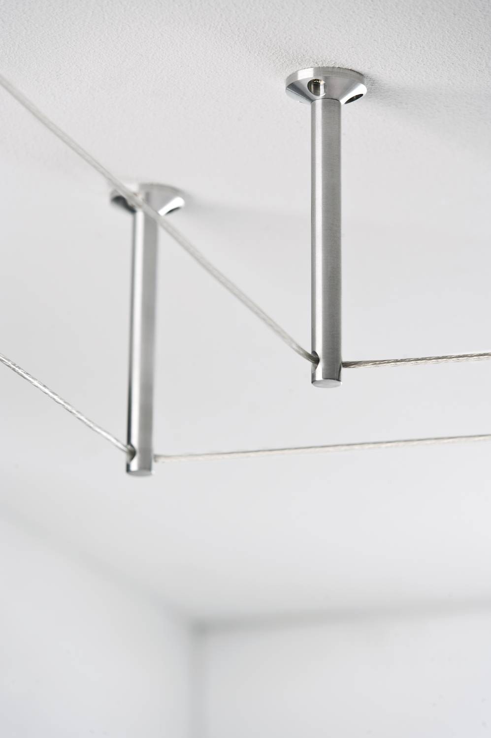 Dvě stříbrné stropní konzole propojují tenké dráty v moderním, minimalistickém designu.