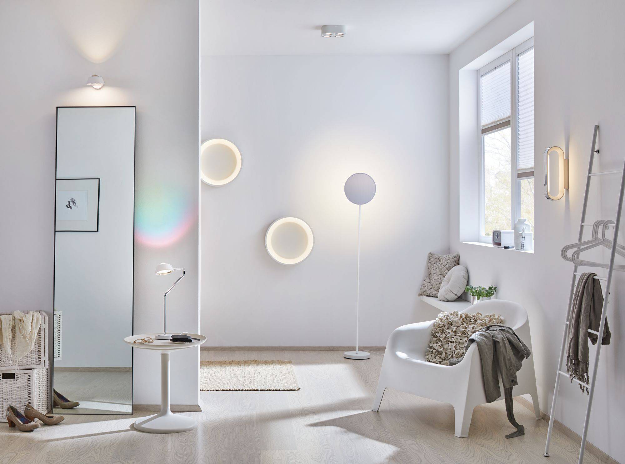 Světlý, moderně zařízený obývací pokoj se stojací lampou, křeslem a dekorací. Minimalistický design s teplými světelnými tóny.