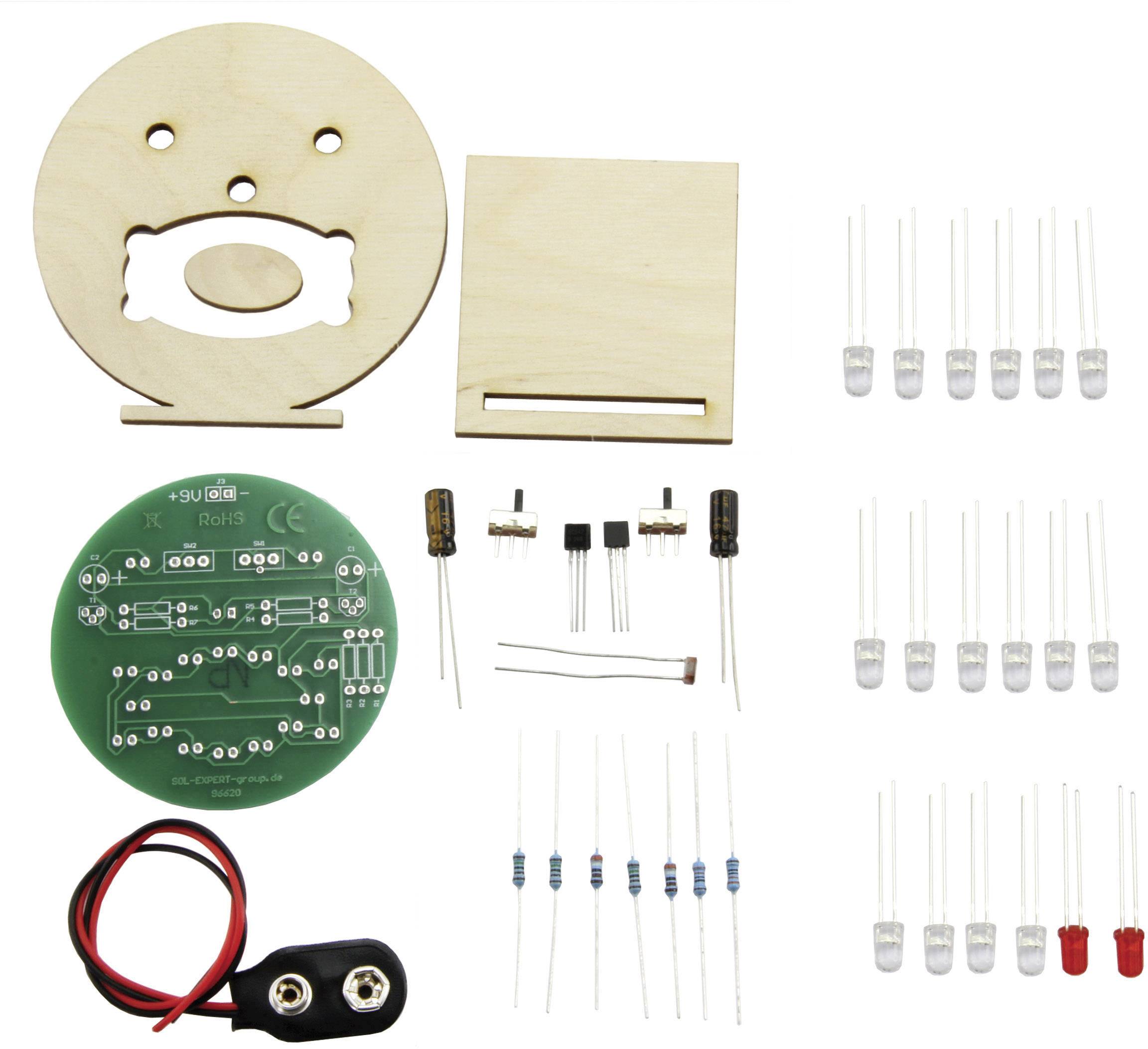 Sada součástek pro elektronický DIY projekt: obsahuje desku plošných spojů, LED osvětlení, rezistory, kabely, dřevěný kryt a další komponenty.