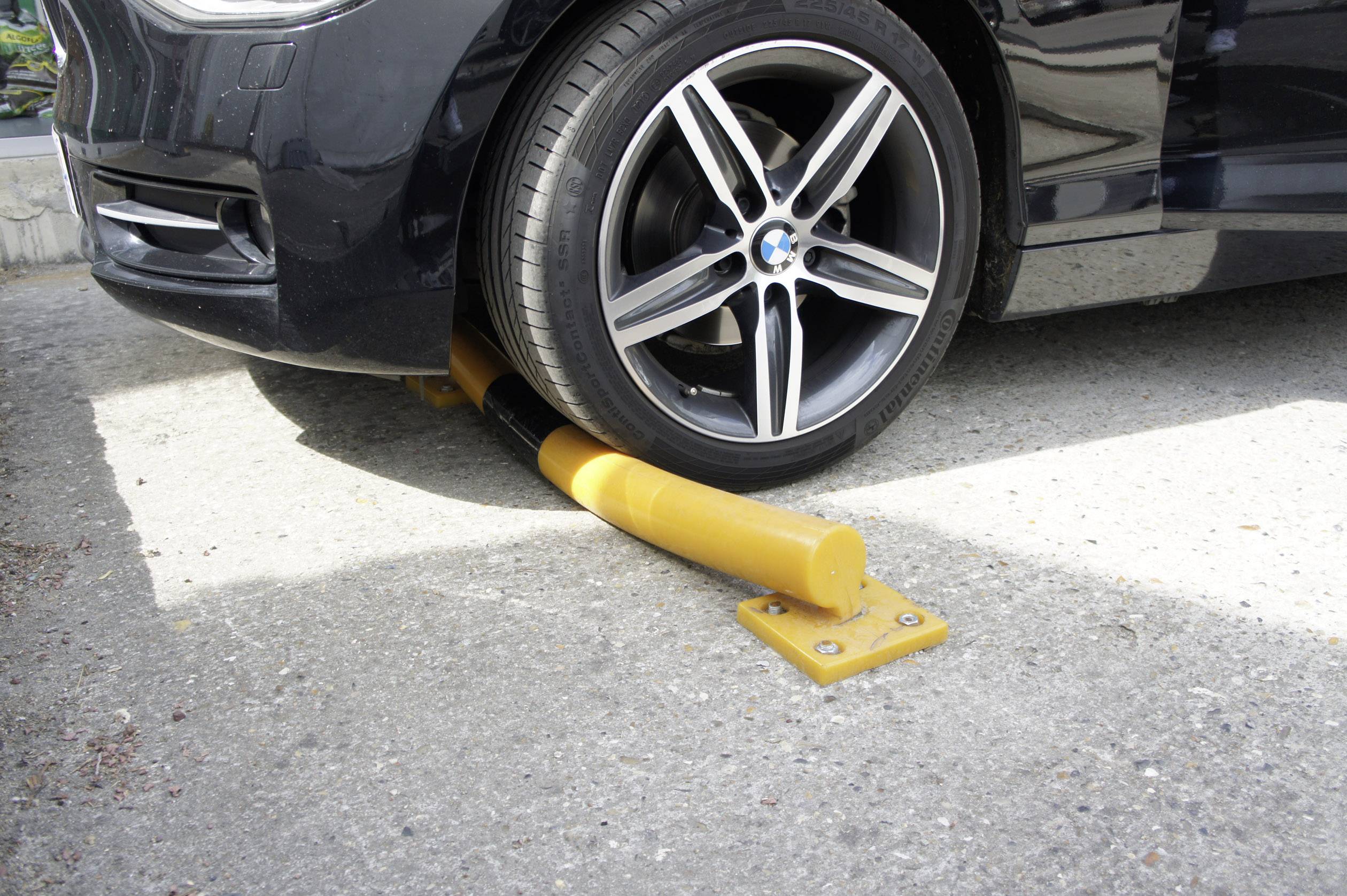 Auto parkuje přes žlutou výstražnou/dopravní značku, která leží pod předním kolem.