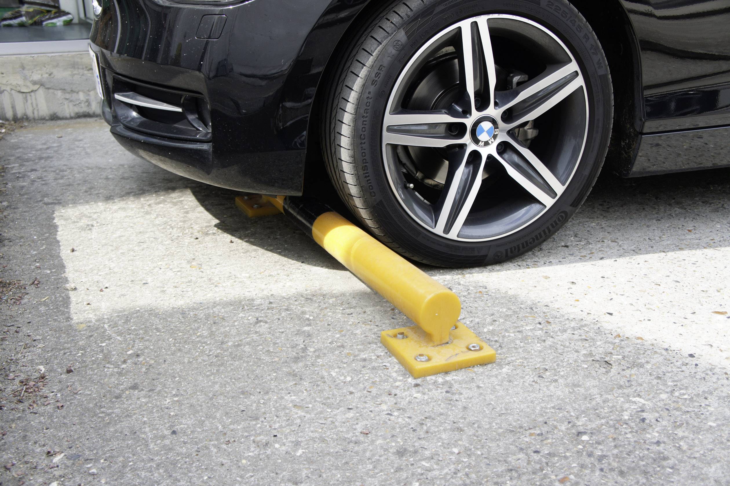 Auto jede přes žlutou pneumatikovou bariéru. Zábrana blokuje vozidlo, aby zabránila neoprávněnému odjezdu.