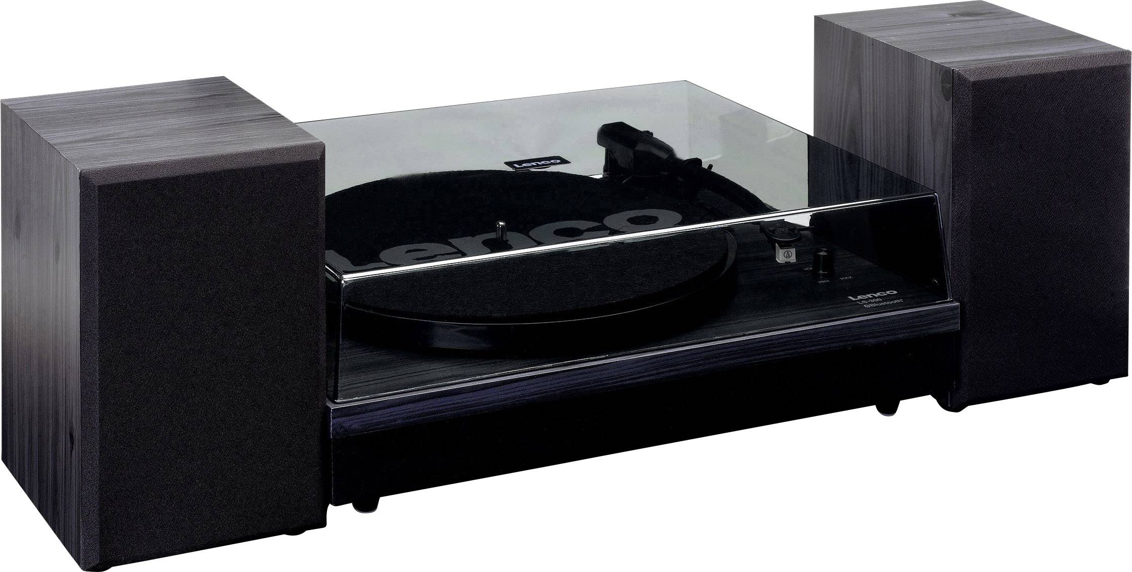 Gramofon se dvěma reproduktory. Moderní, hranatý design, černý povrch. Zapnutý a připravený k přehrávání.