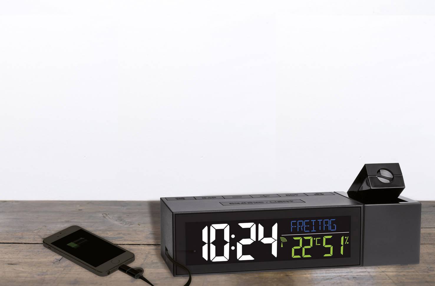 Budík na dřevěném stole ukazuje '10:24 pátek 22. září'. Smartphone se nabíjí přes USB kabel.