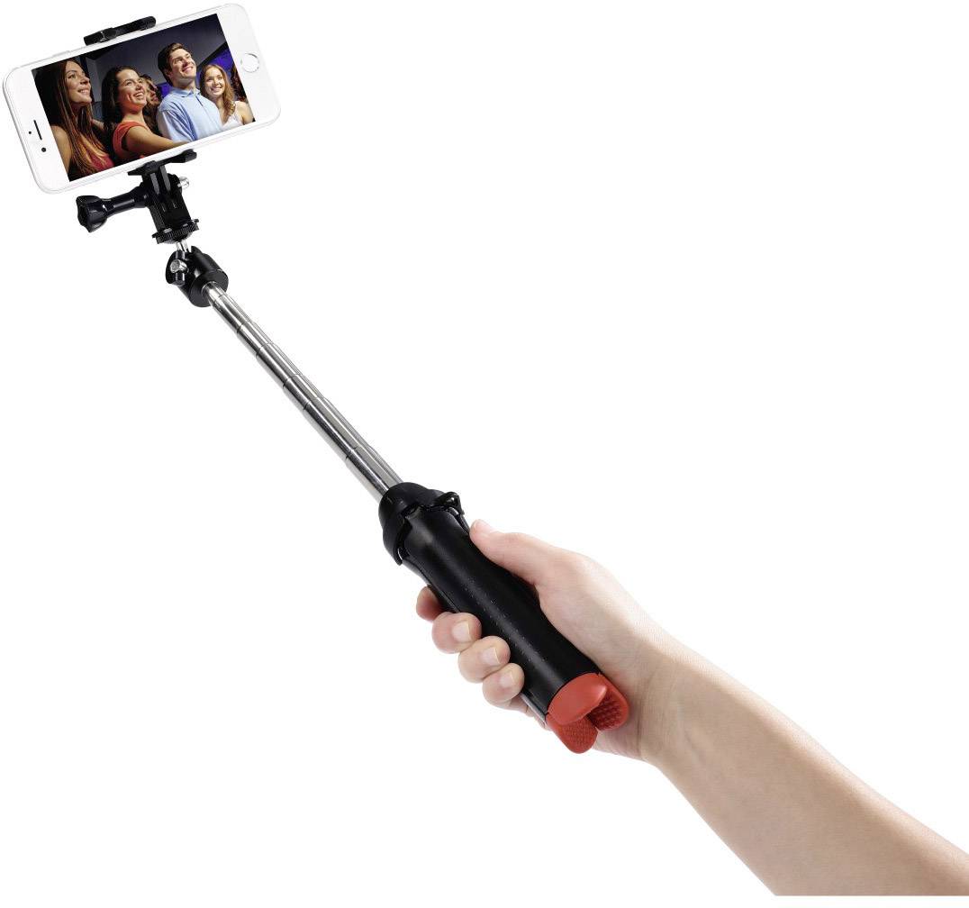 Jedna ruka drží selfie tyč se smartphonem, který zobrazuje skupinovou fotografii čtyř se usmívajících osob.