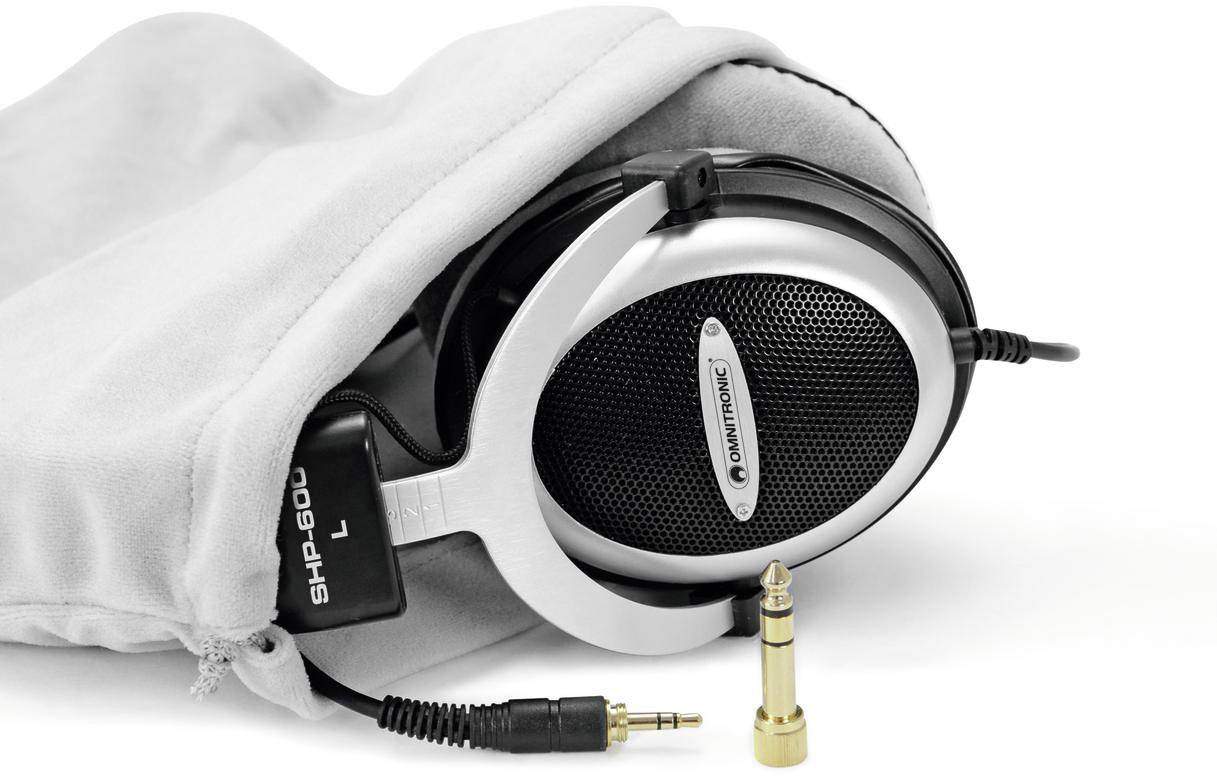 Stříbrné over-ear sluchátka částečně umístěná v šedém ochranném obalu, vedle s odpojitelným audiovým kabelem a adaptérem.