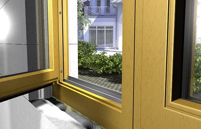 Dřevěný okenní rám je otevřený, pohled ven na zelskou zahradu a modrý dům. Denní světlo proniká do místnosti.