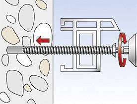 Šroub je zašroubován do stěny naplněné štěrkem. Šipka ukazuje směr šroubování a matice je upevňována.